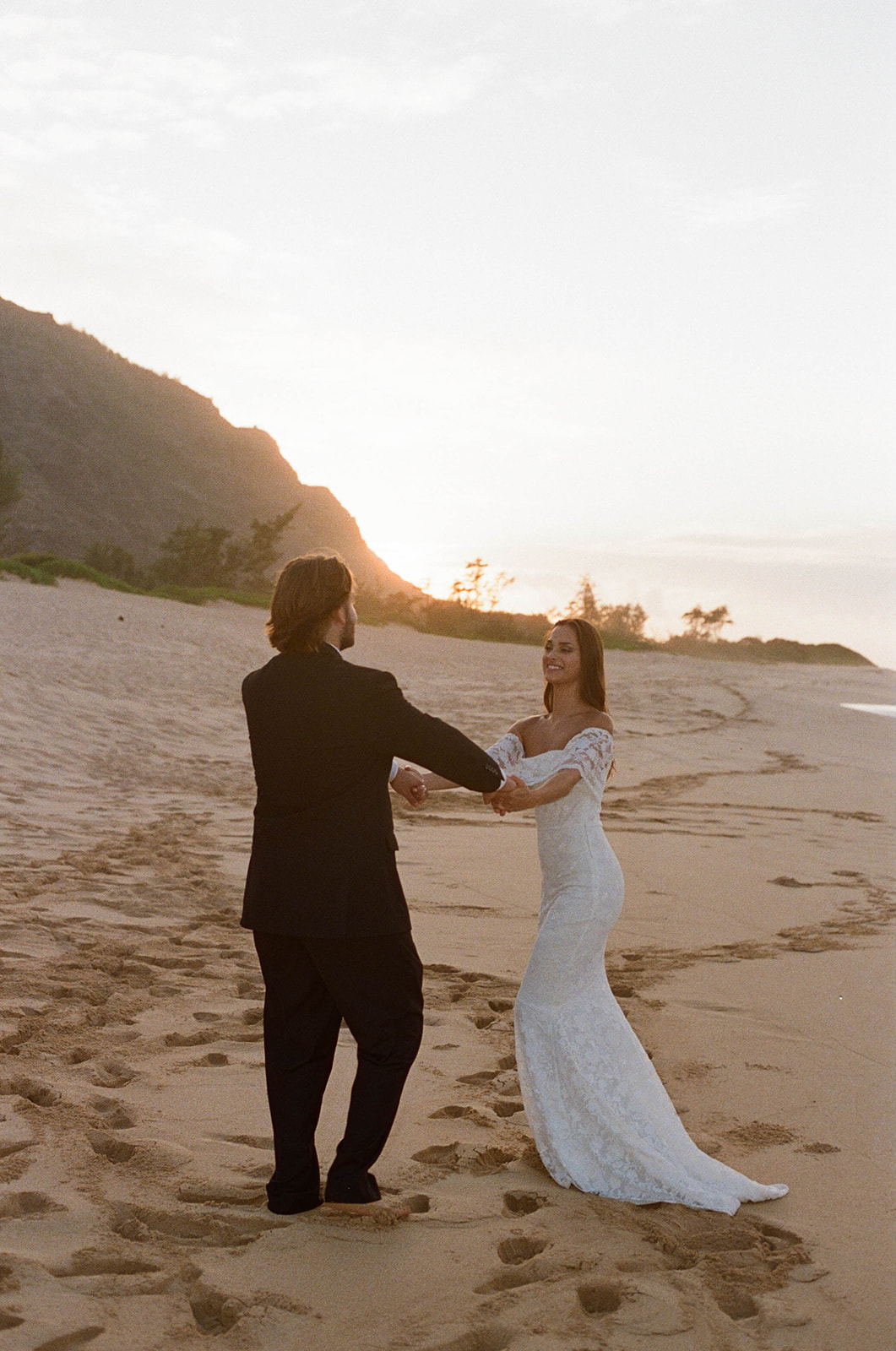 The bride and groom dancing on the beach at sunrise during their Kauai wedding.