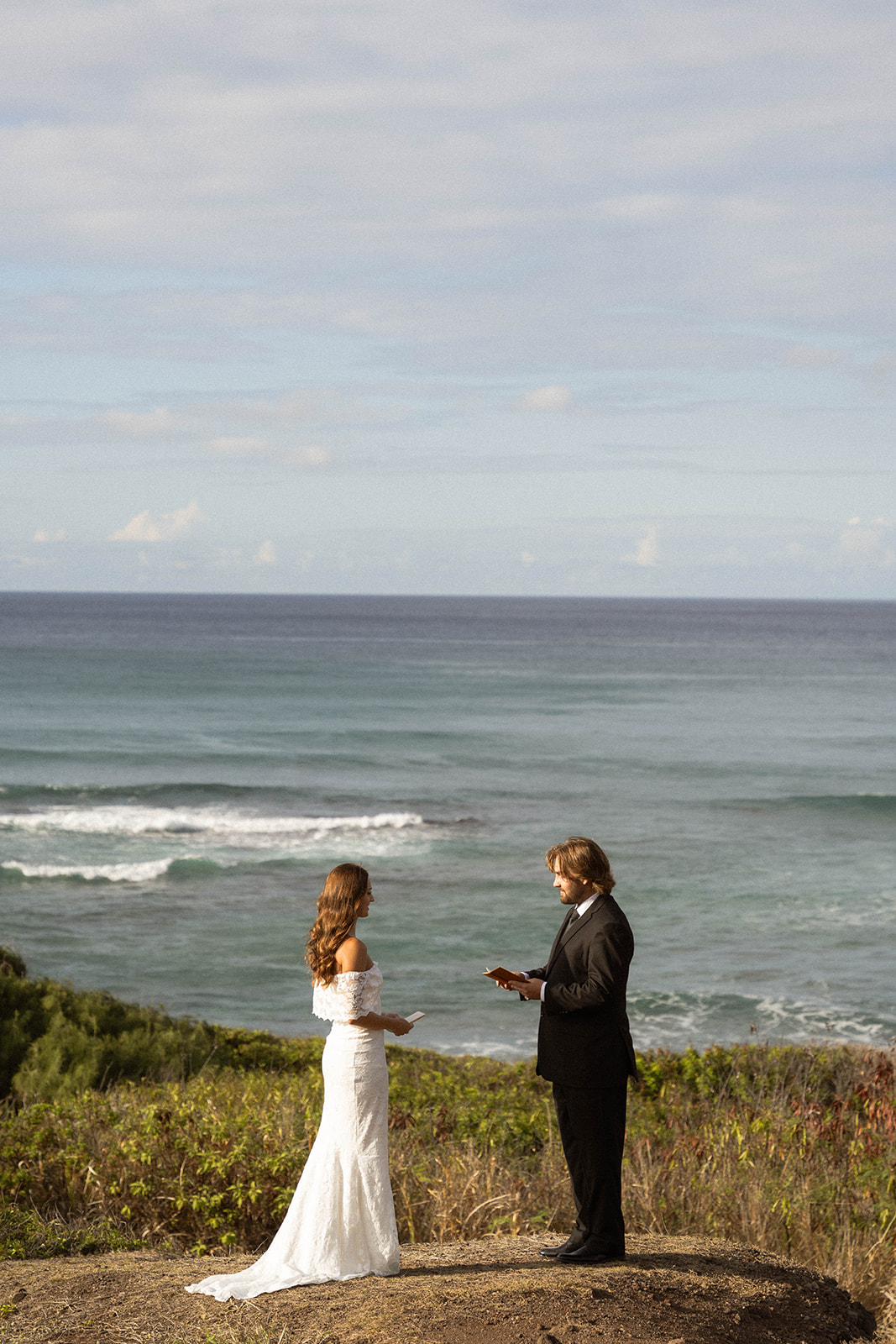Bride and groom exchanging vows with the ocean behind them during their intimate Kauai Wedding Planning ceremony on the cliffs.