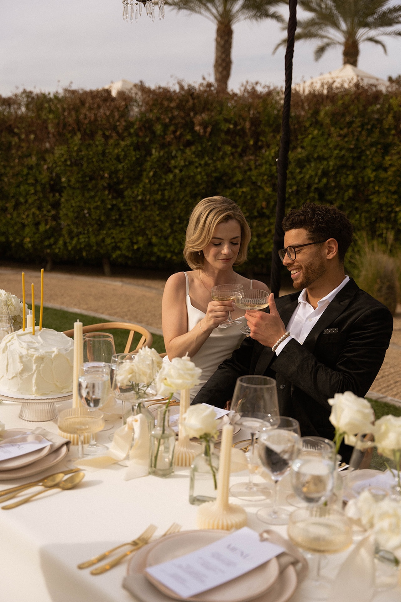 Bride and groom toasting together at their intimate outdoor dinner surrounded by florals and candlelight.