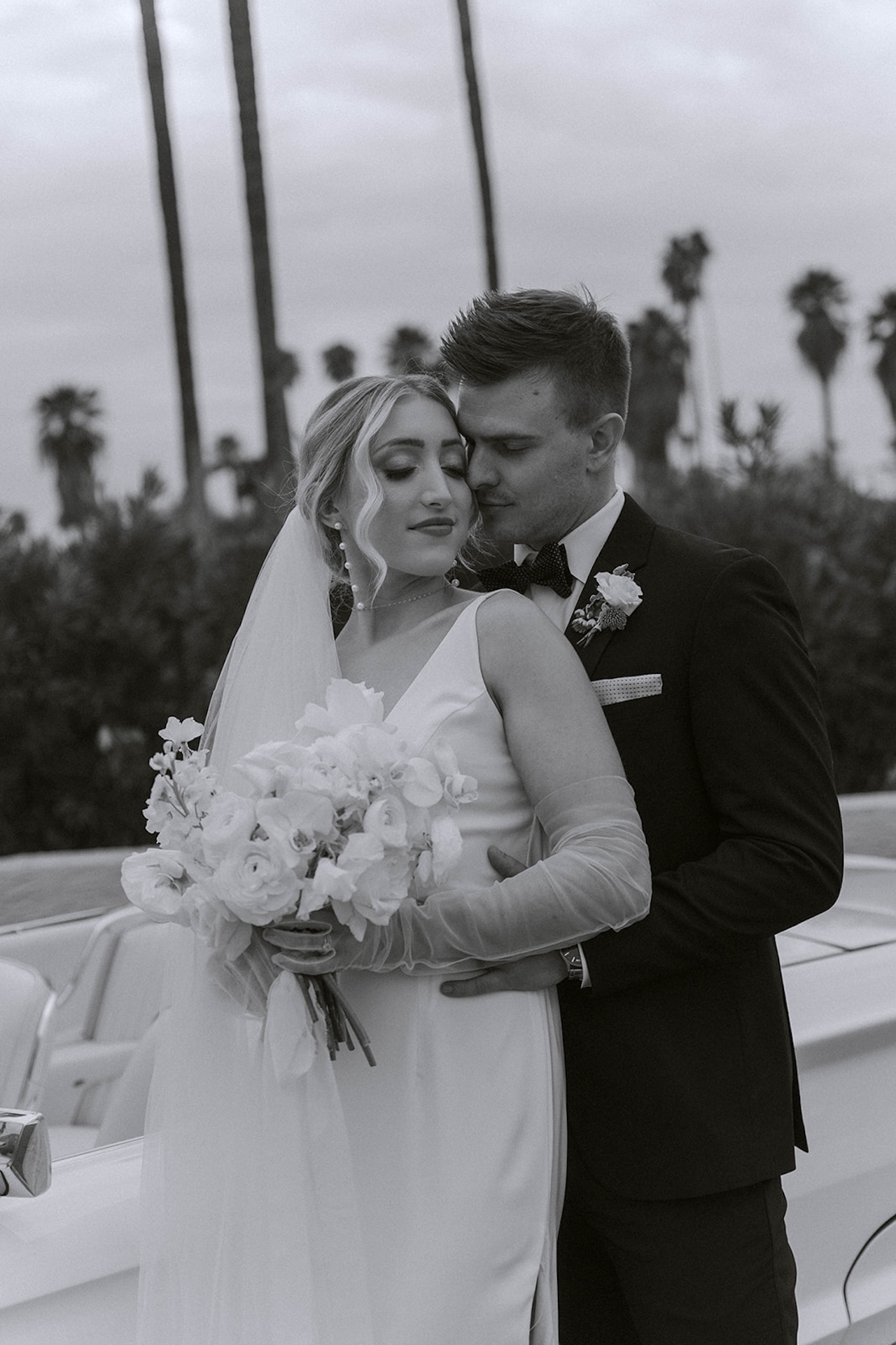 Couple embracing beside palm trees during their intimate wedding.