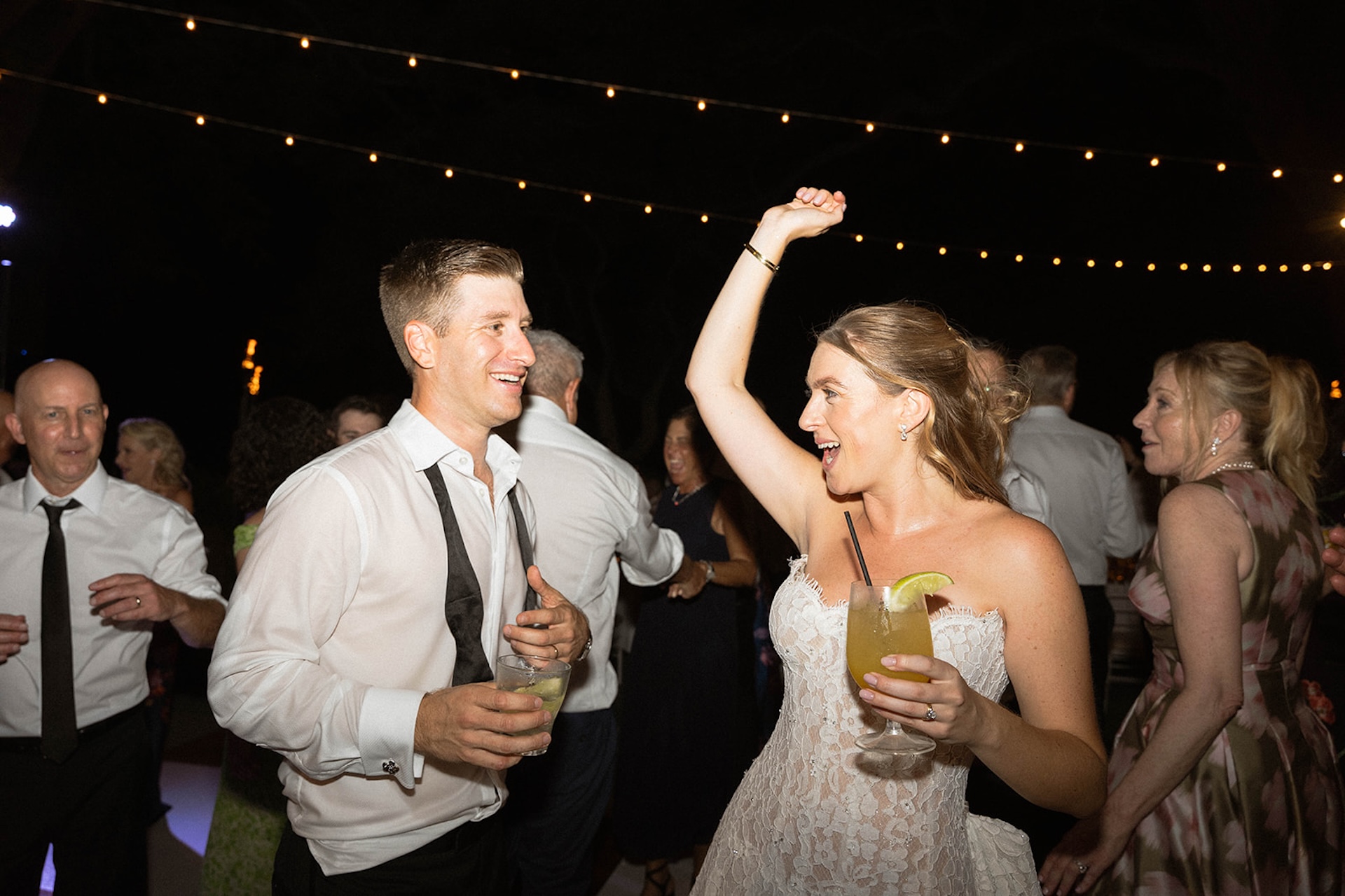 The bride and groom dancing on the dance floor with drinks in their hand during their Big Island Destination Wedding.
