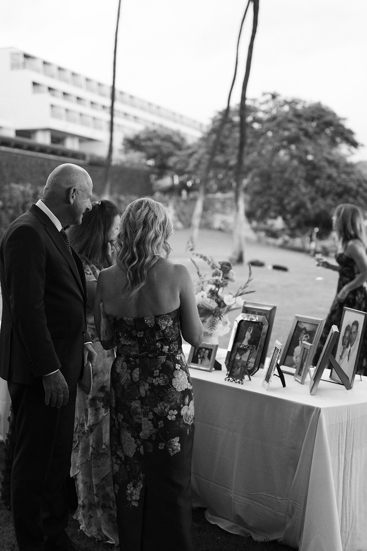 Guests gathered around a memory table displaying framed photos during an outdoor wedding reception