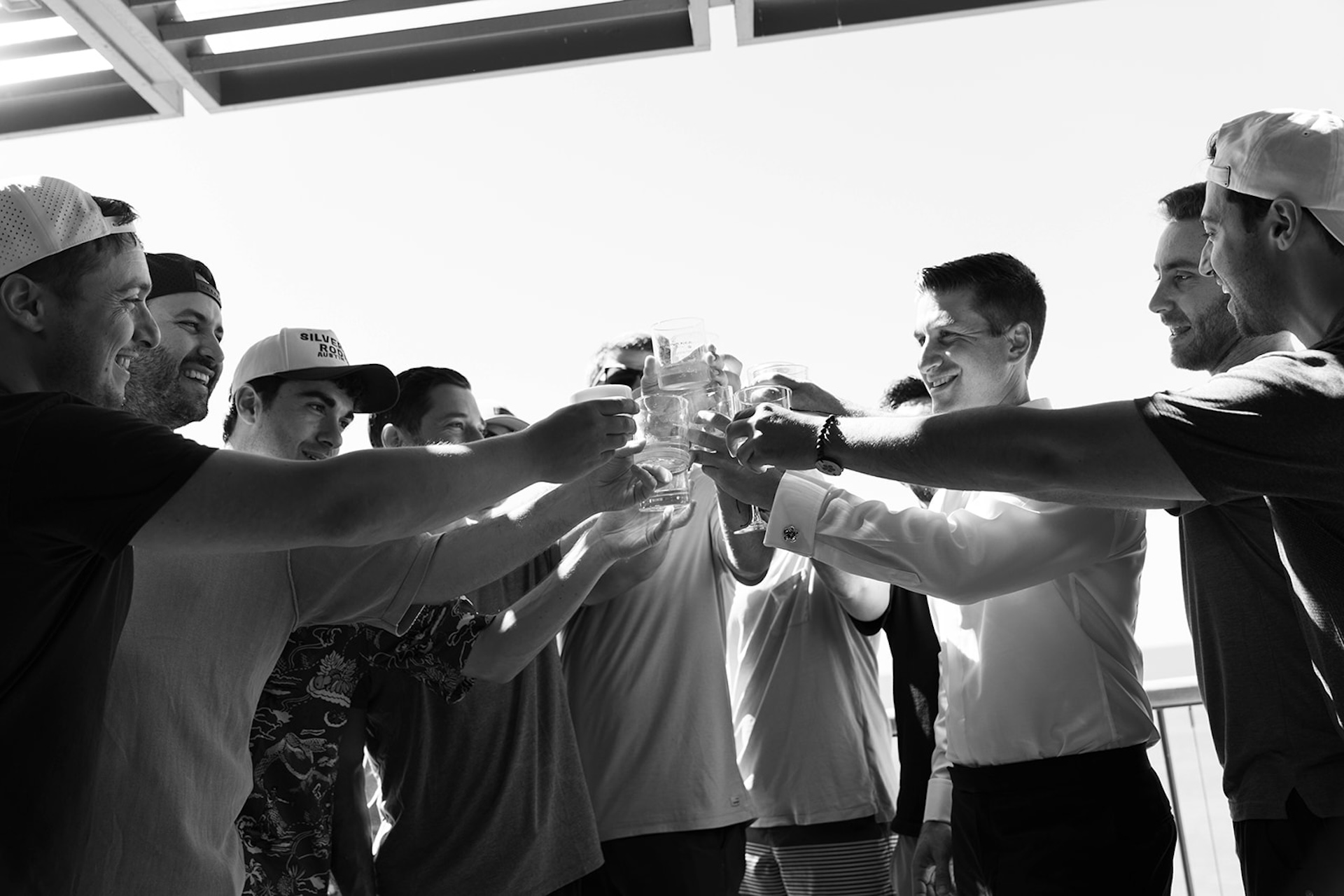 The groom toasts with his groomsmen in a candid black and white photo, a relaxed pre-ceremony moment shaped by big island wedding planning.