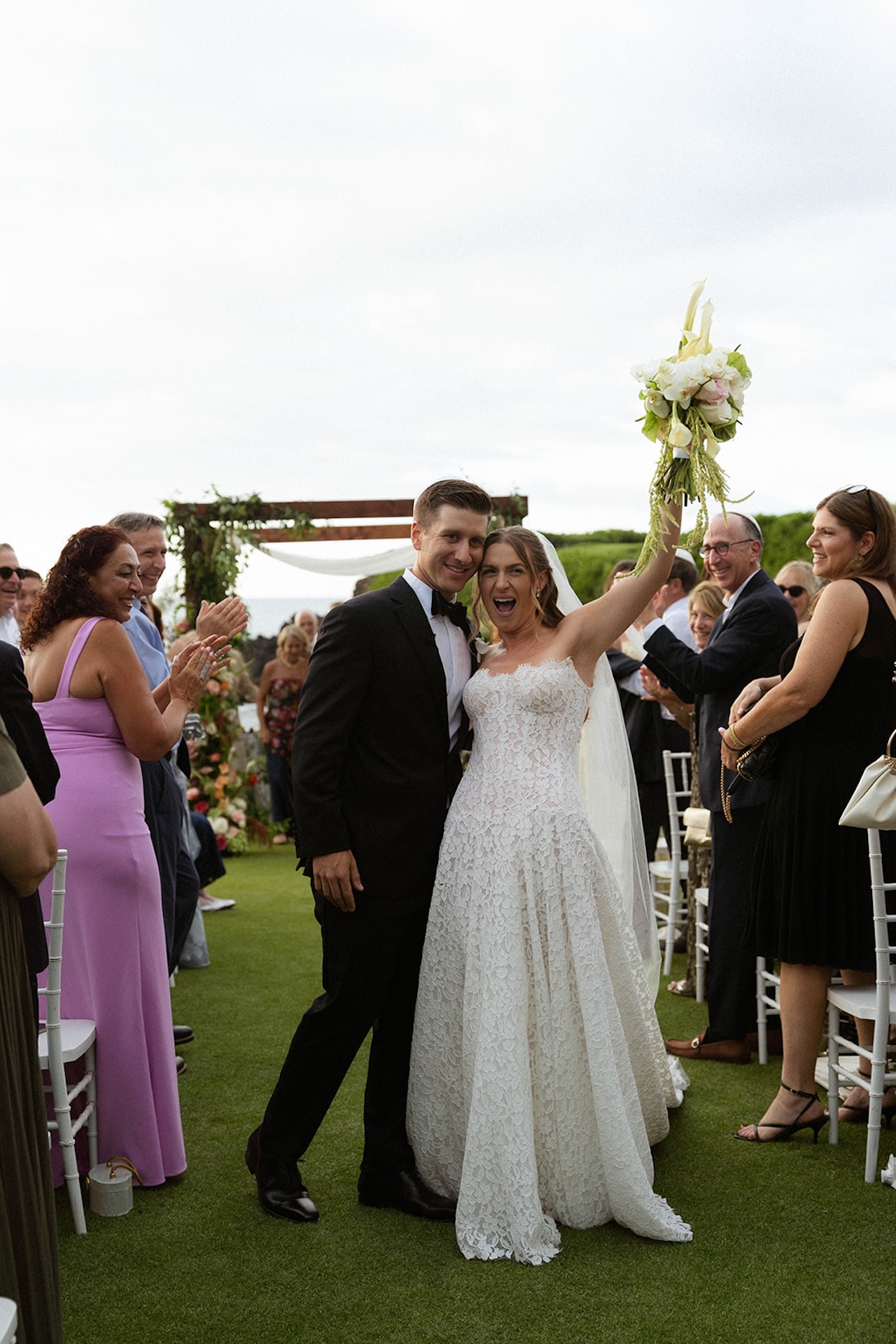 The newly married couple walks back down the aisle cheering with guests after their ceremony.