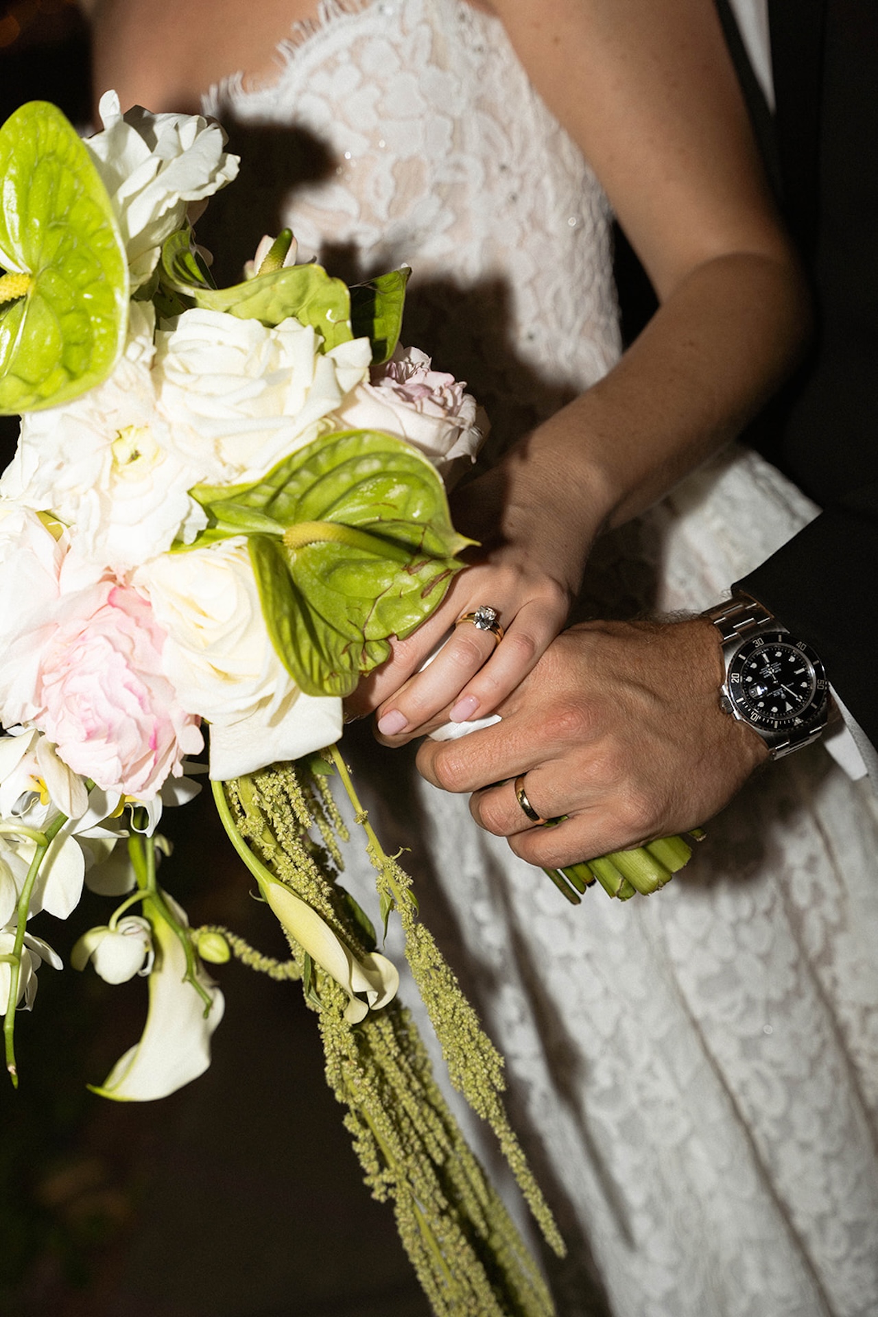 A flash photo of the bride holding her bridal bouquet that has light pink roses, white roses, and some greenery.