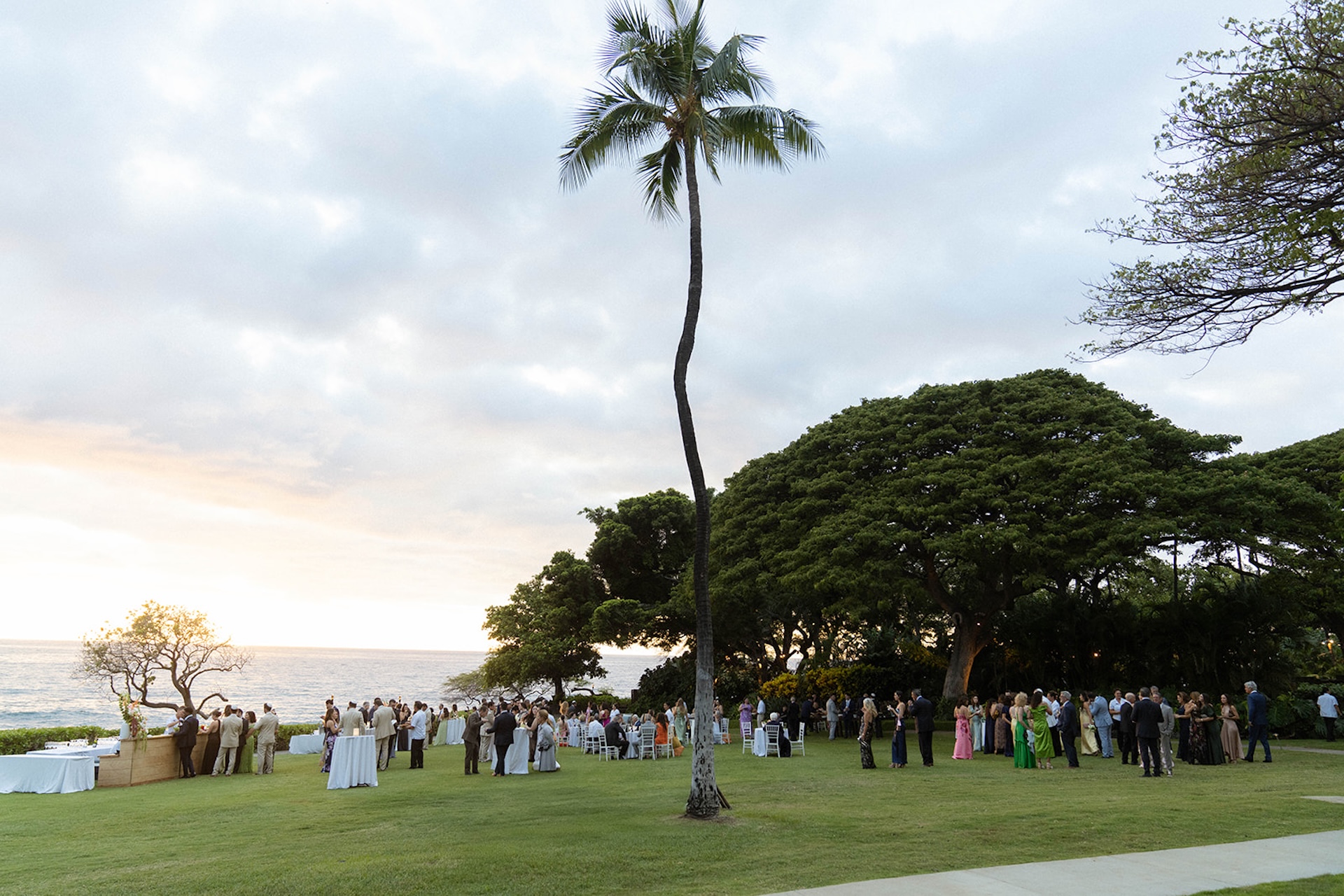 An elevated ceremony scene overlooking the ocean and palm trees, showcasing the scenic locations couples consider during big island wedding planning.