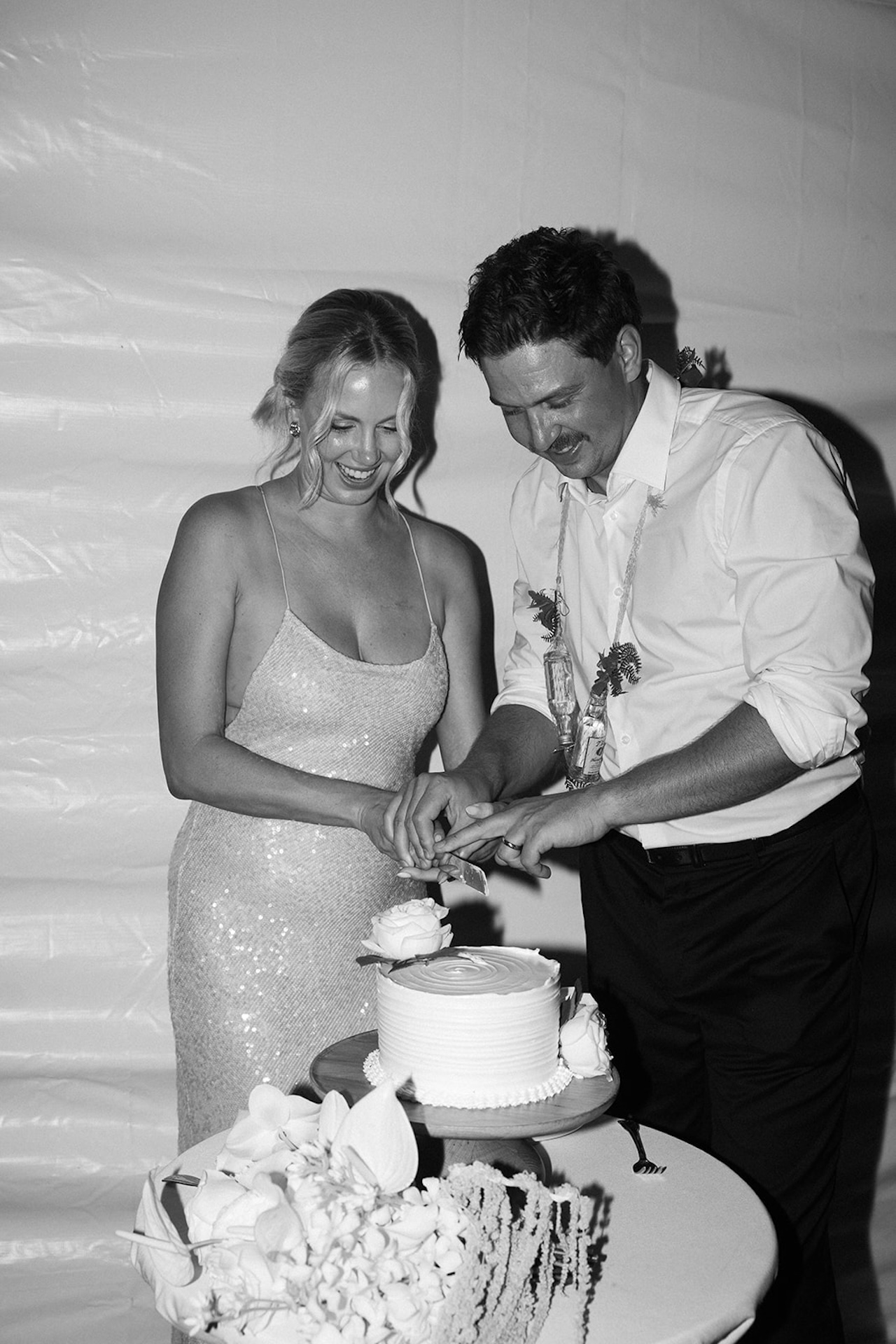 A black and white moment of the couple cutting their wedding cake together beneath a tent at one of the most intimate Kauai wedding venues.
