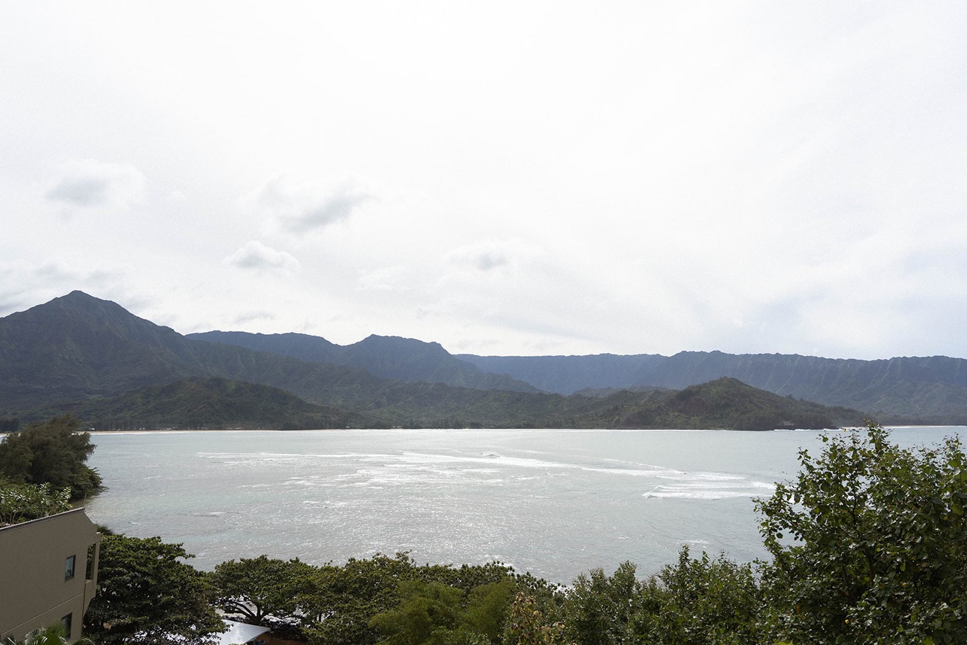 Wide ocean view with dramatic mountains and soft waves, showcasing the natural scenery surrounding a tropical island wedding location.