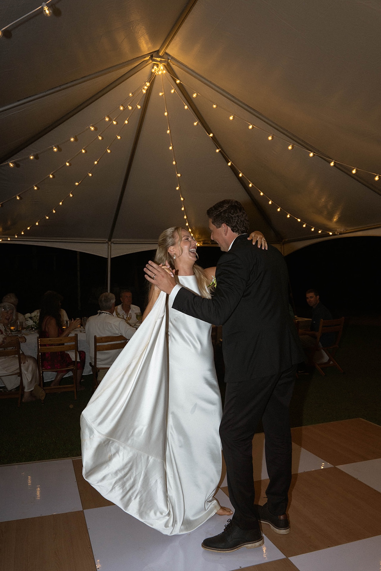 The bride and groom share their first dance under twinkle lights on the dance floor at one of the most heartfelt Kauai wedding venues.