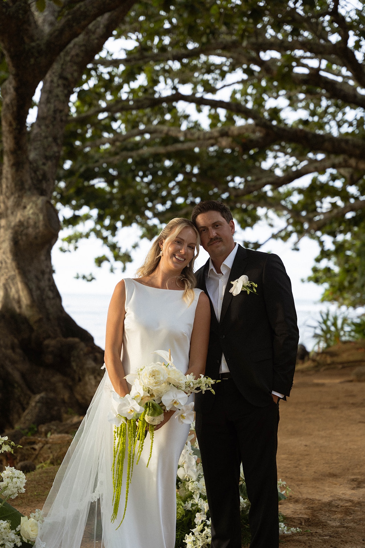 The bride and groom smiling softly during golden hour at the camera for some bride and groom portraits after their wedding ceremony.