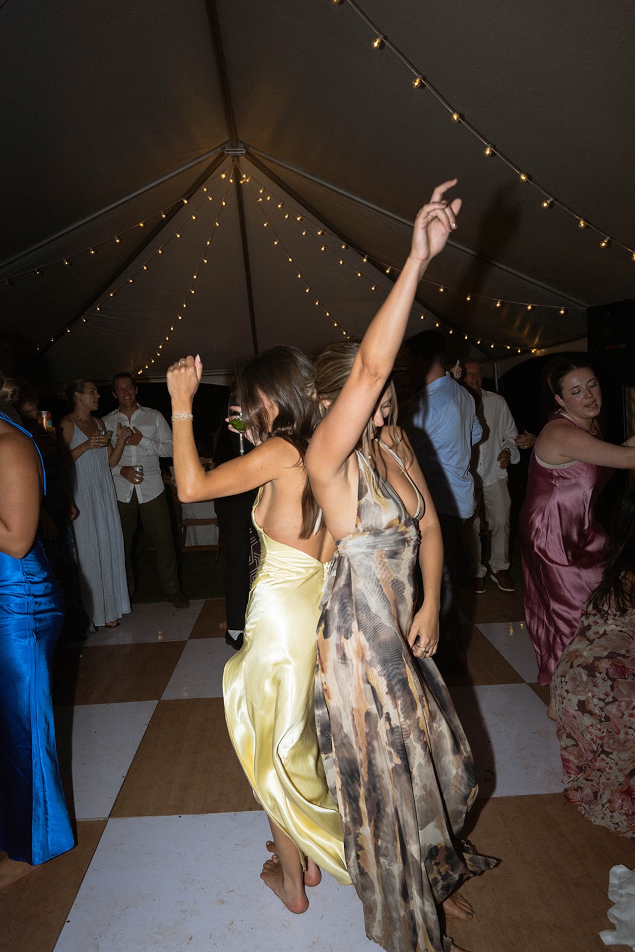 Wedding guests dance barefoot under a tent with string lights, celebrating freely at one of the most relaxed Kauai wedding venues.