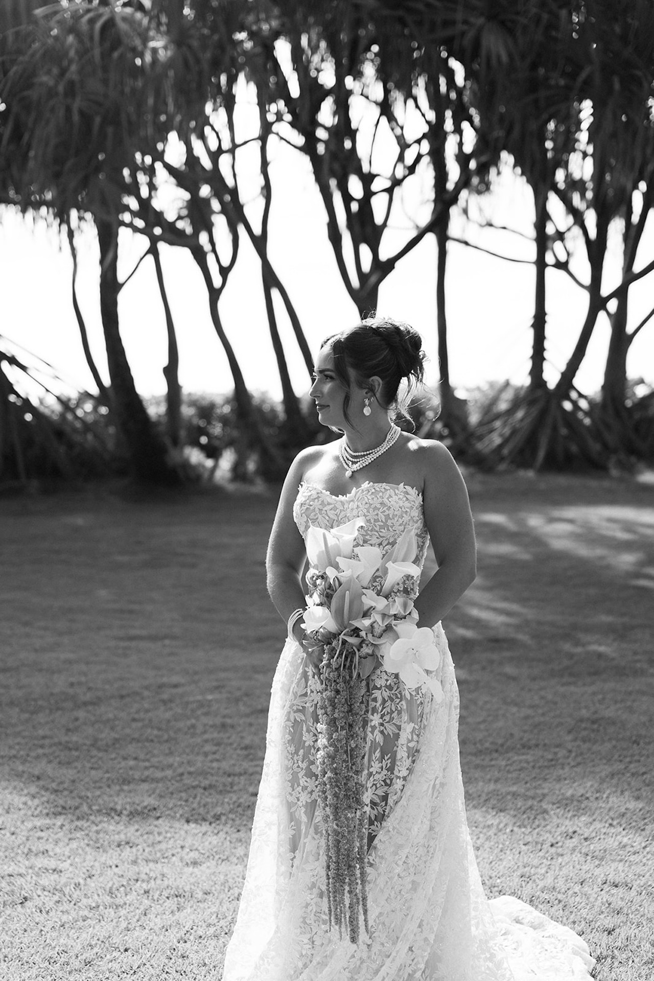 A editorial shot of the bride standing on an open lawn while holding her wedding bouquet during her bridal portraits.