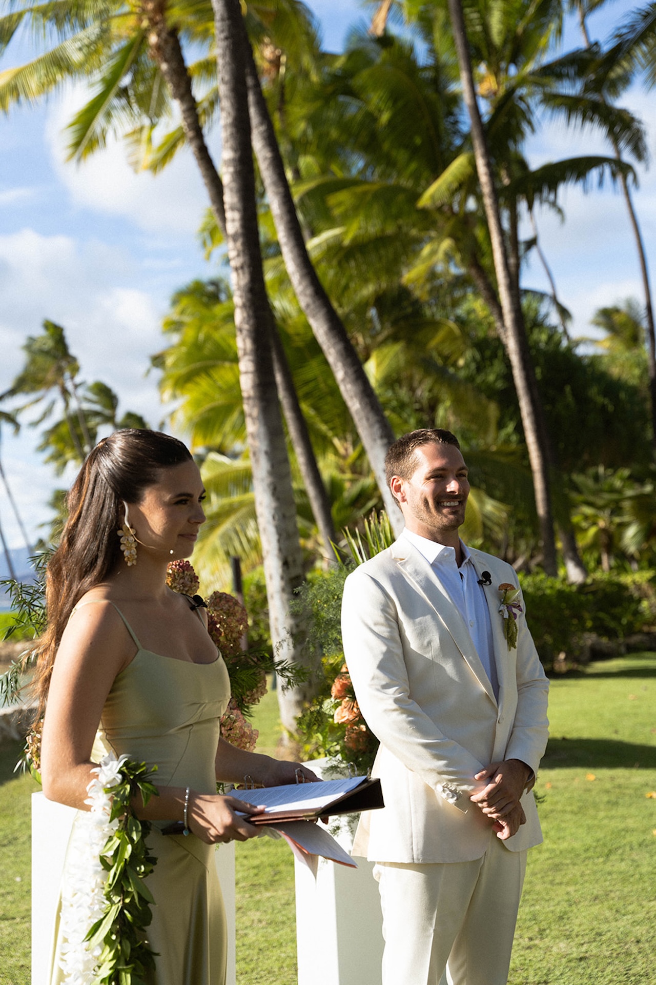 The officiant smiles while standing beside the groom during the outdoor ceremony.