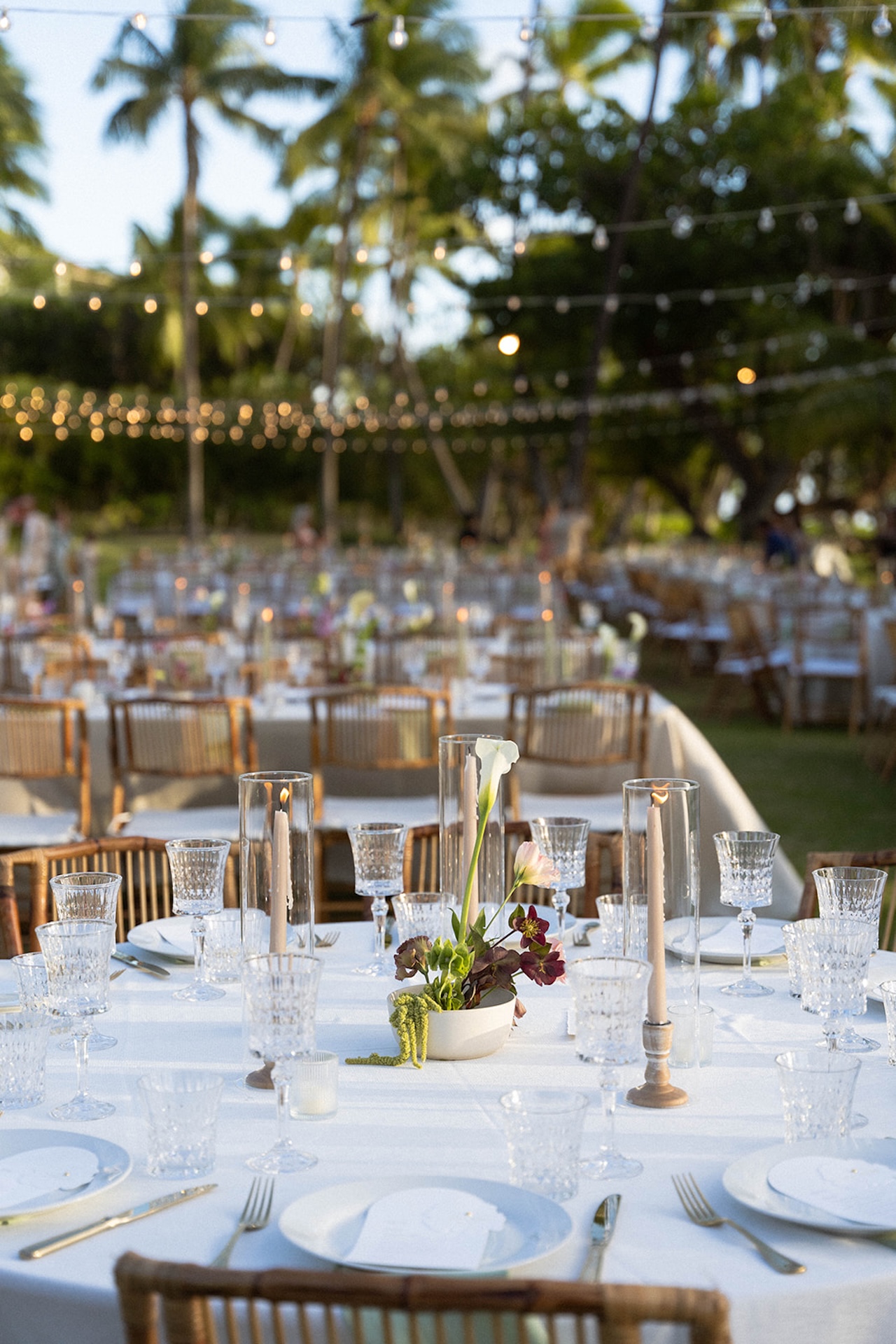 Round reception table decorated with candles and flowers at the Lanikuhonua wedding celebration.