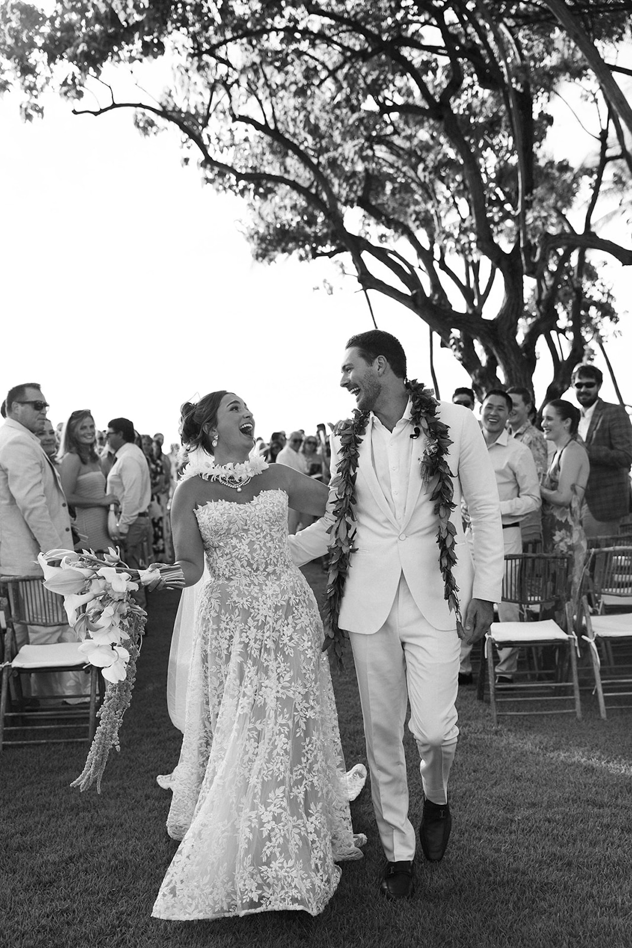 The newly married couple walks up the aisle laughing together as guests cheer.