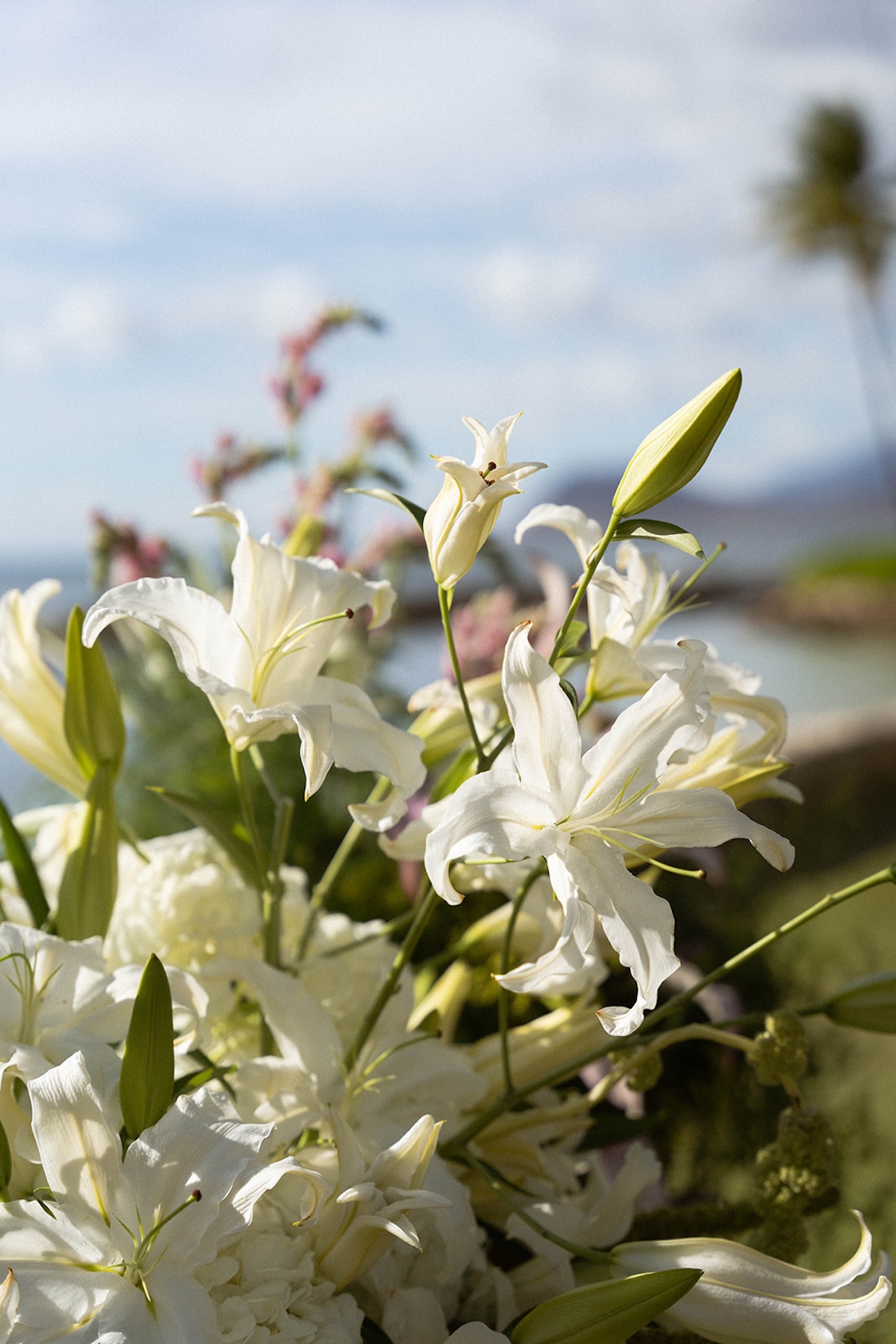 Close-up of white lilies and greenery arranged for the outdoor ceremony.