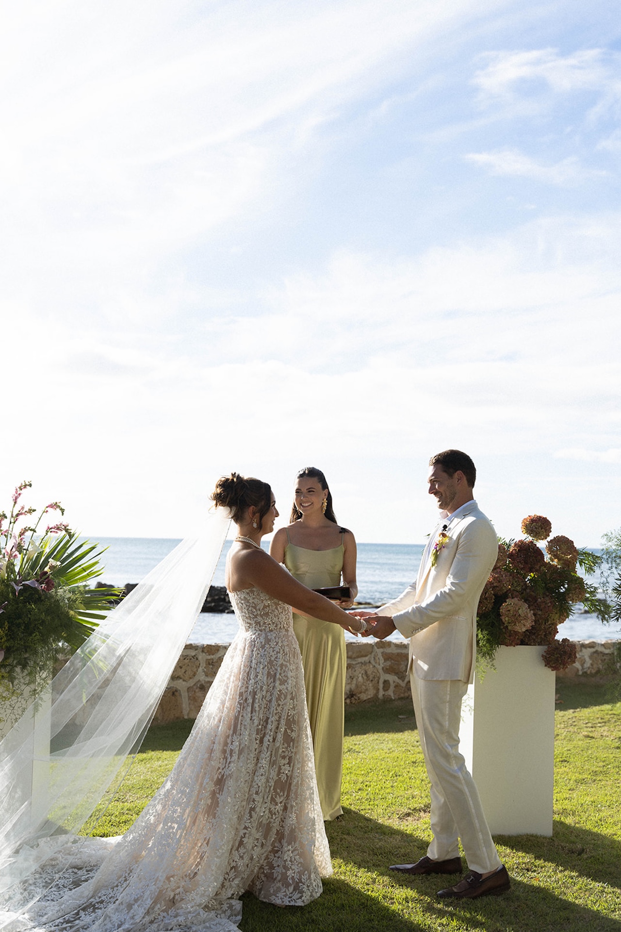 The bride’s veil flows behind her as she stands with the groom at their Lanikuhonua wedding.