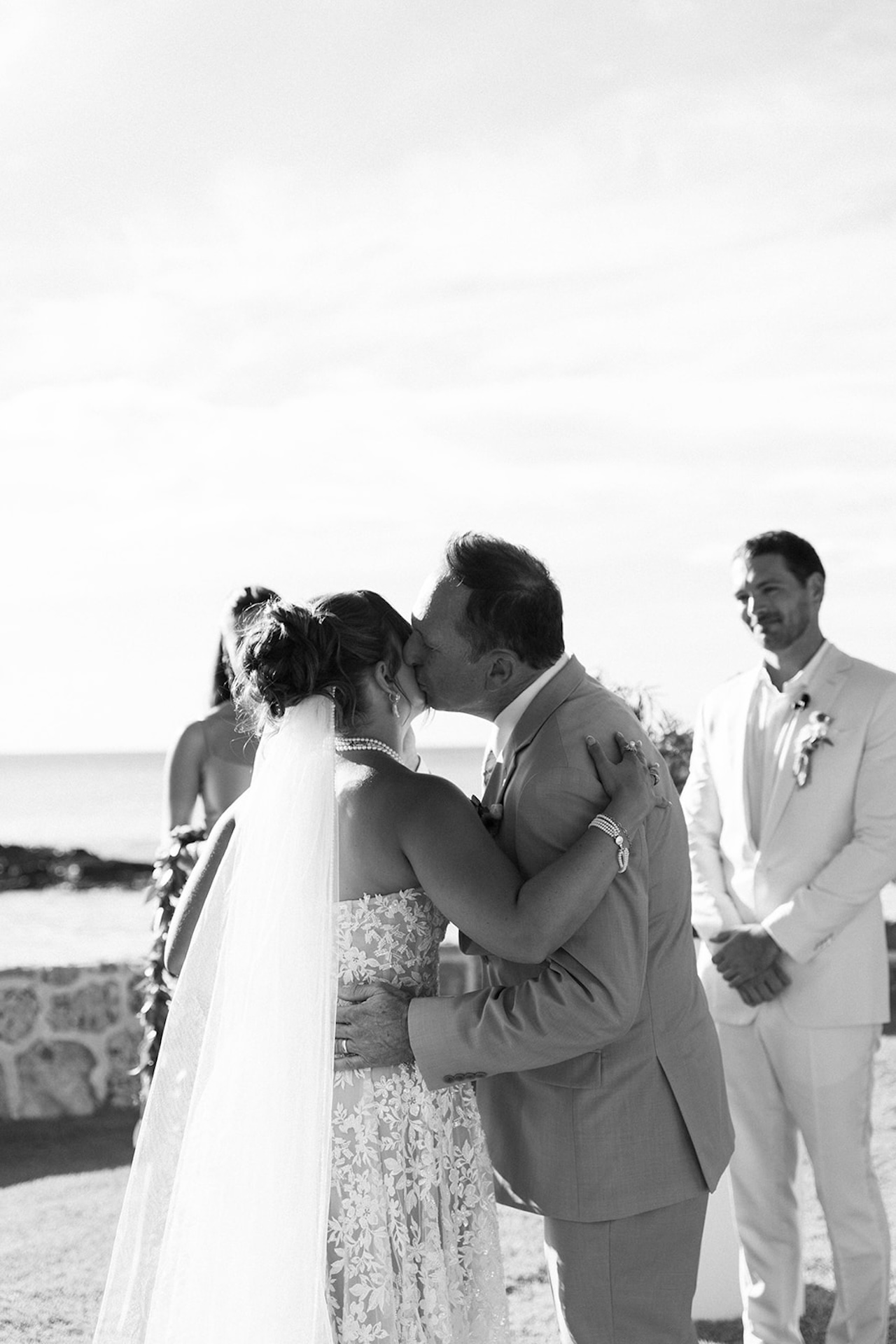 Black-and-white photo of the bride hugging her father during the Lanikuhonua wedding ceremony.
