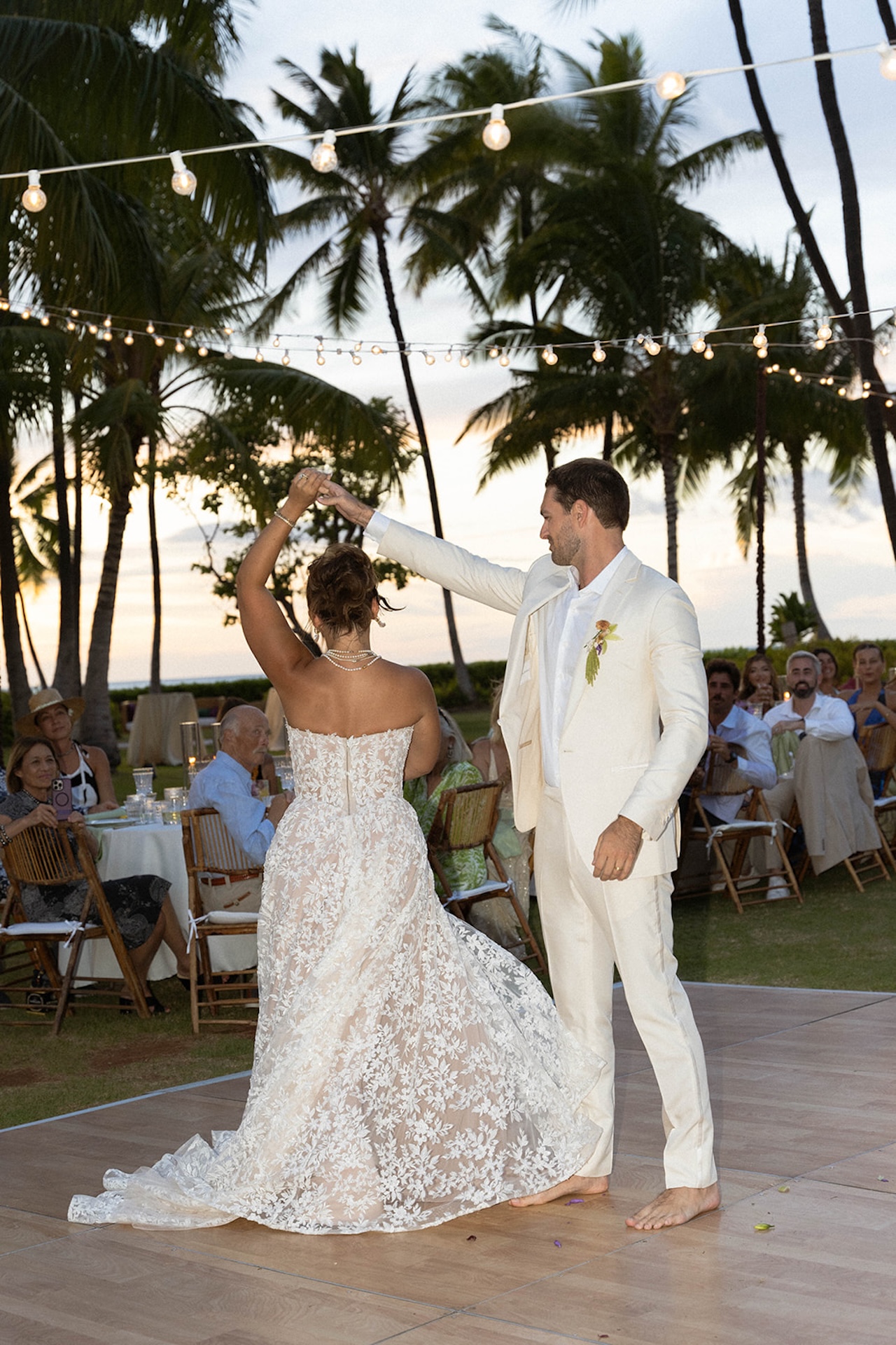 The couple shares their first dance surrounded by guests at their Lanikuhonua wedding reception.