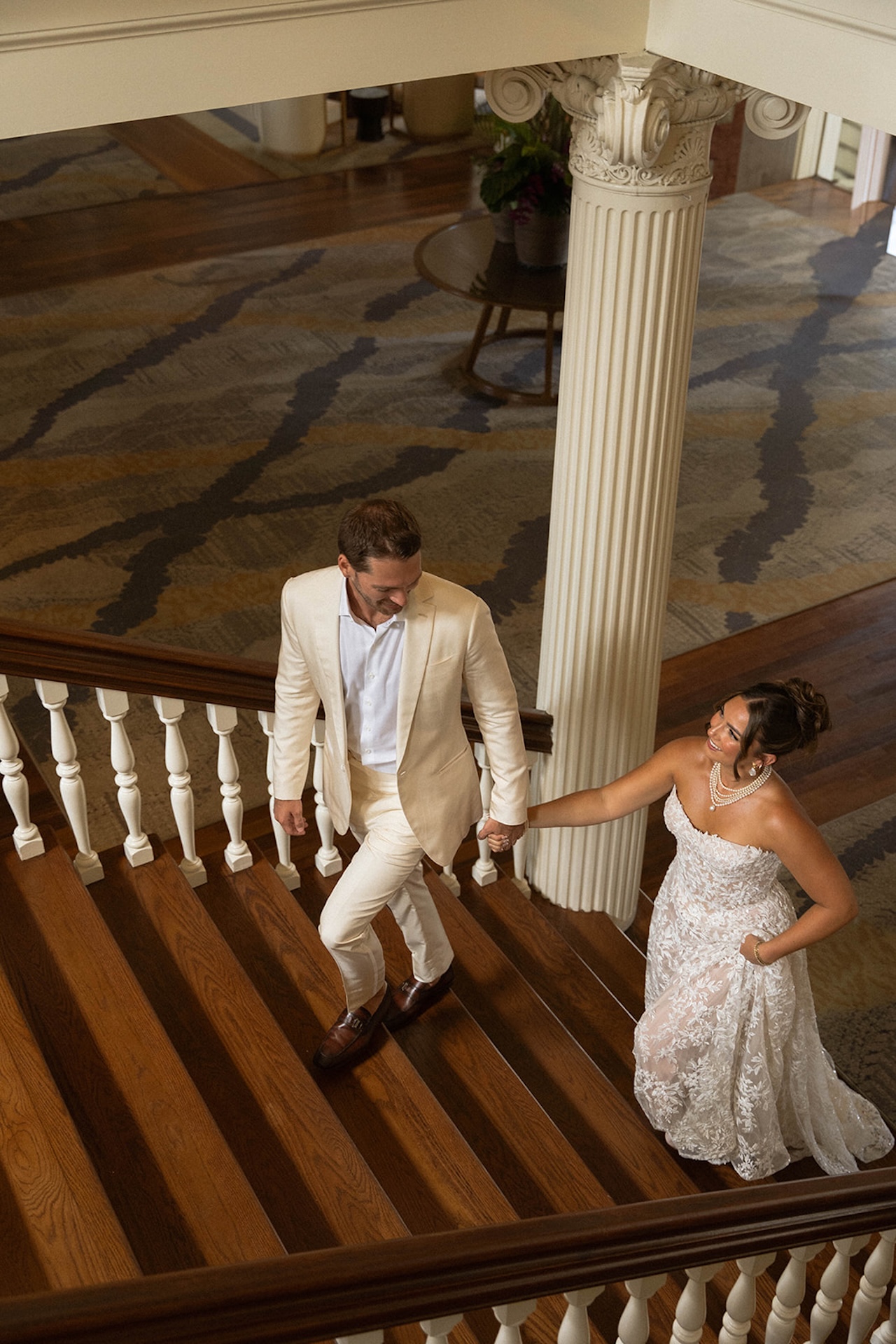 The bride and groom holding hands while walking up some old stairs during their Lanikuhonua wedding.