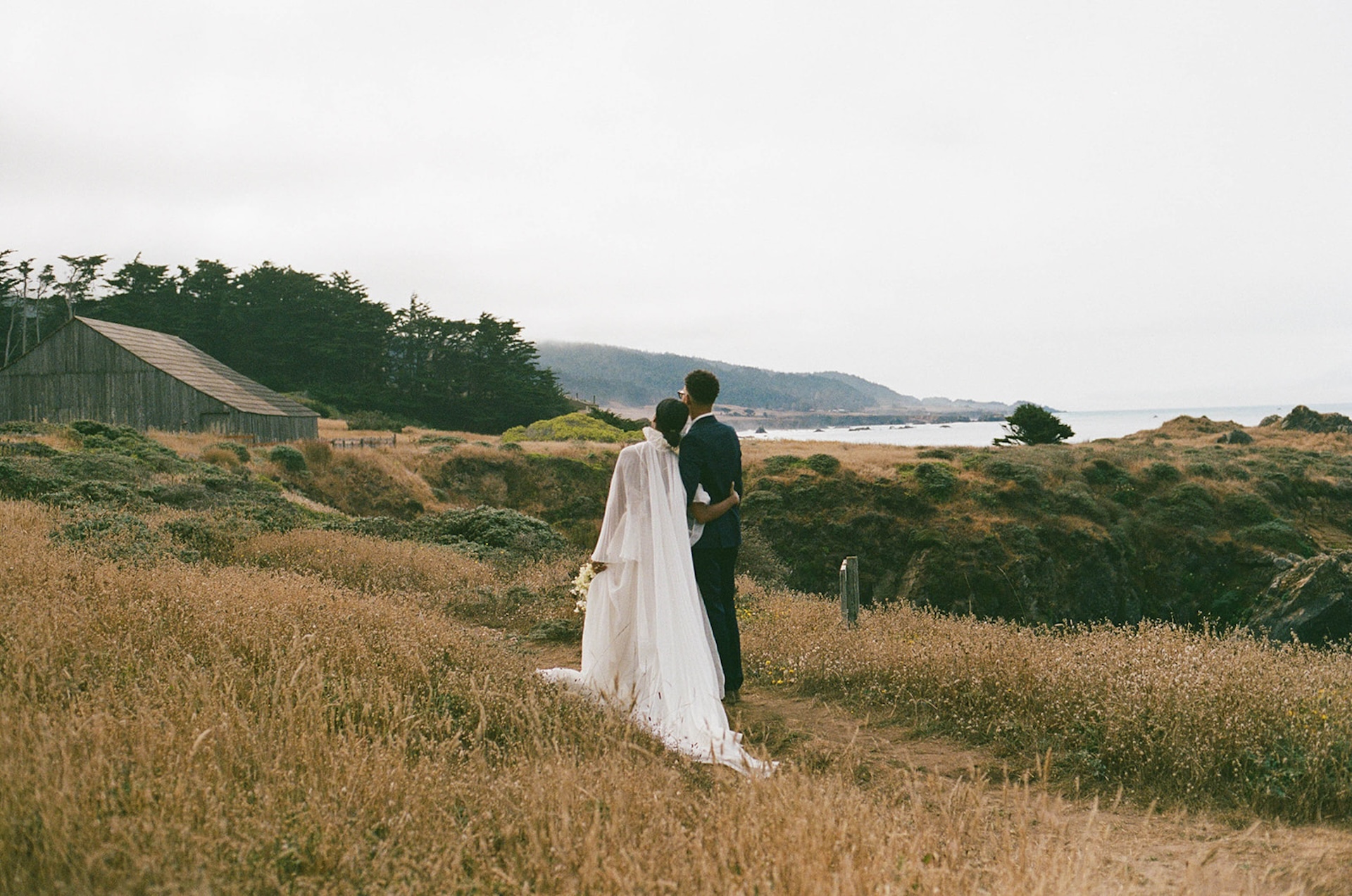 The bride and groom hugging and standing on a dirt path that leads back to their Sea Ranch Lodge Wedding