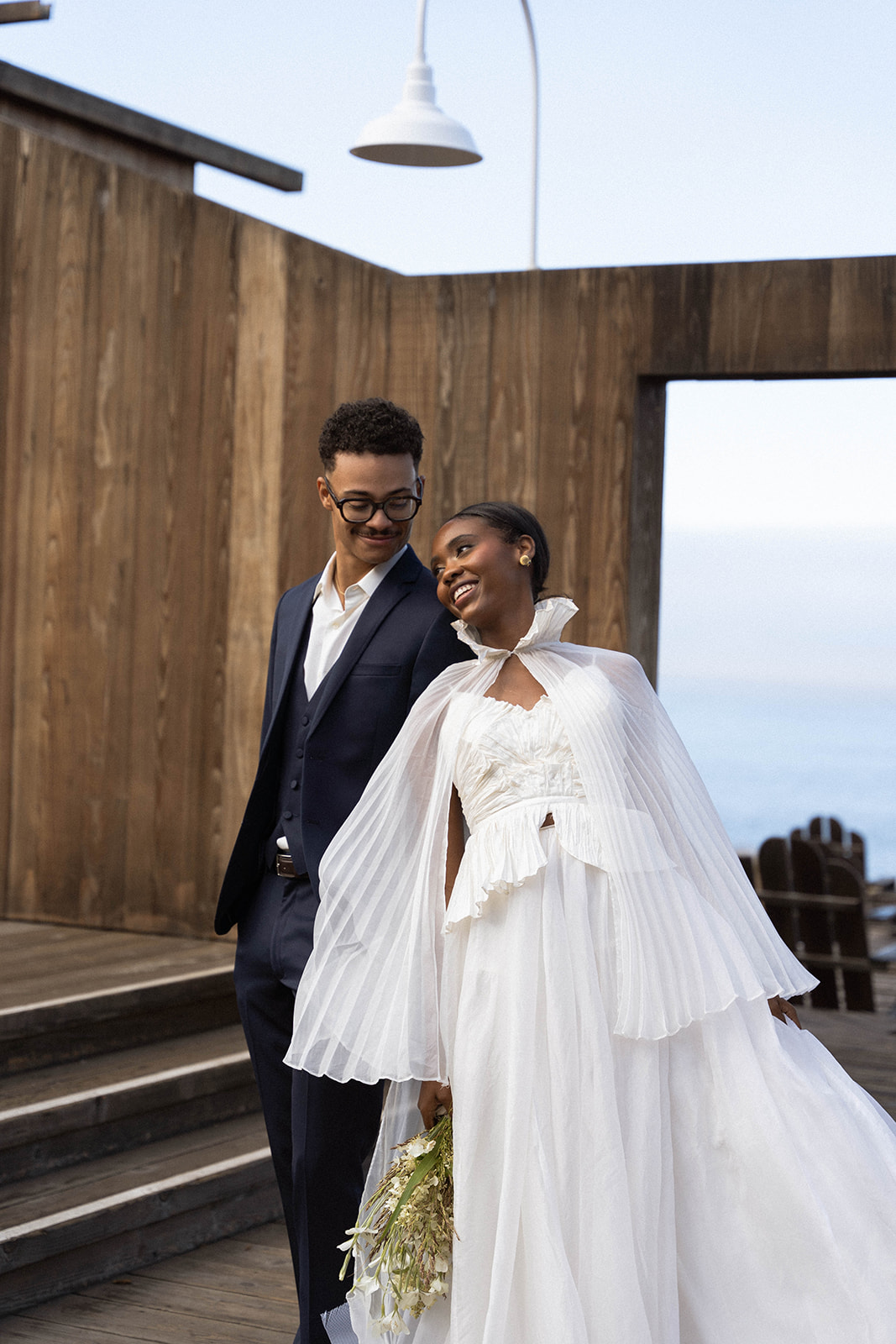 The bride laughing and leaning into the groom as they stand together during bride and groom portraits during their Sea Ranch Lodge Wedding
