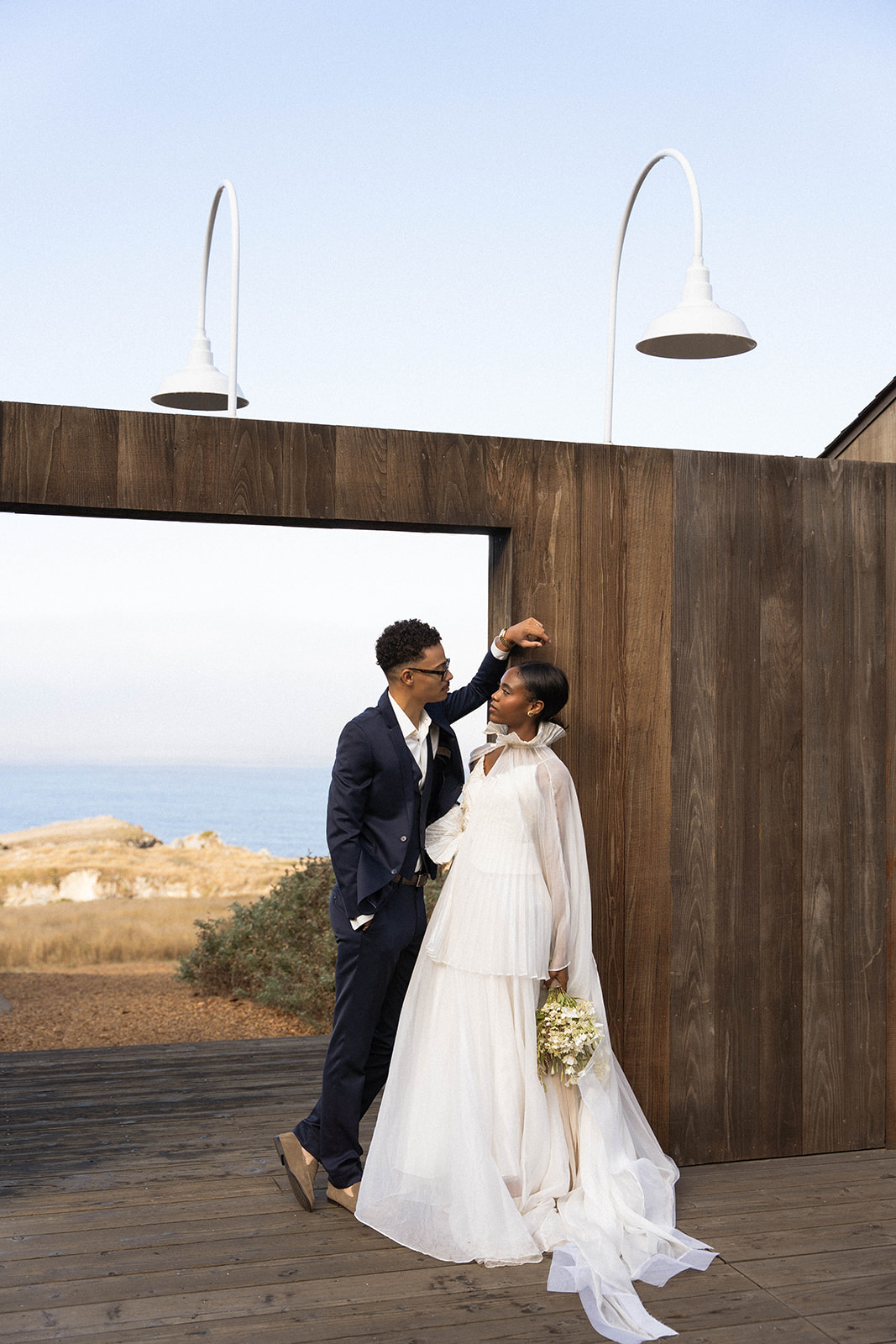 The groom leaning against a wood archway while looking down at the bride who is leaning against the the wood as well during their Sea Ranch Lodge Wedding
