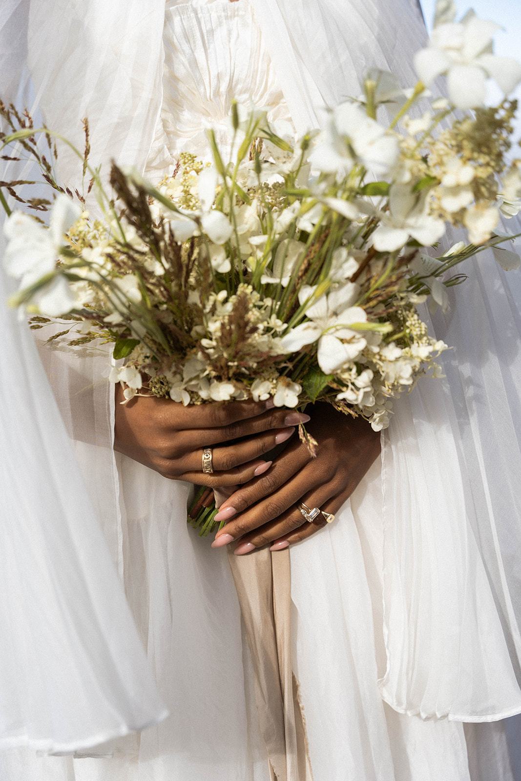 A close up of the brides hands holding her elegant green and white wedding florals.