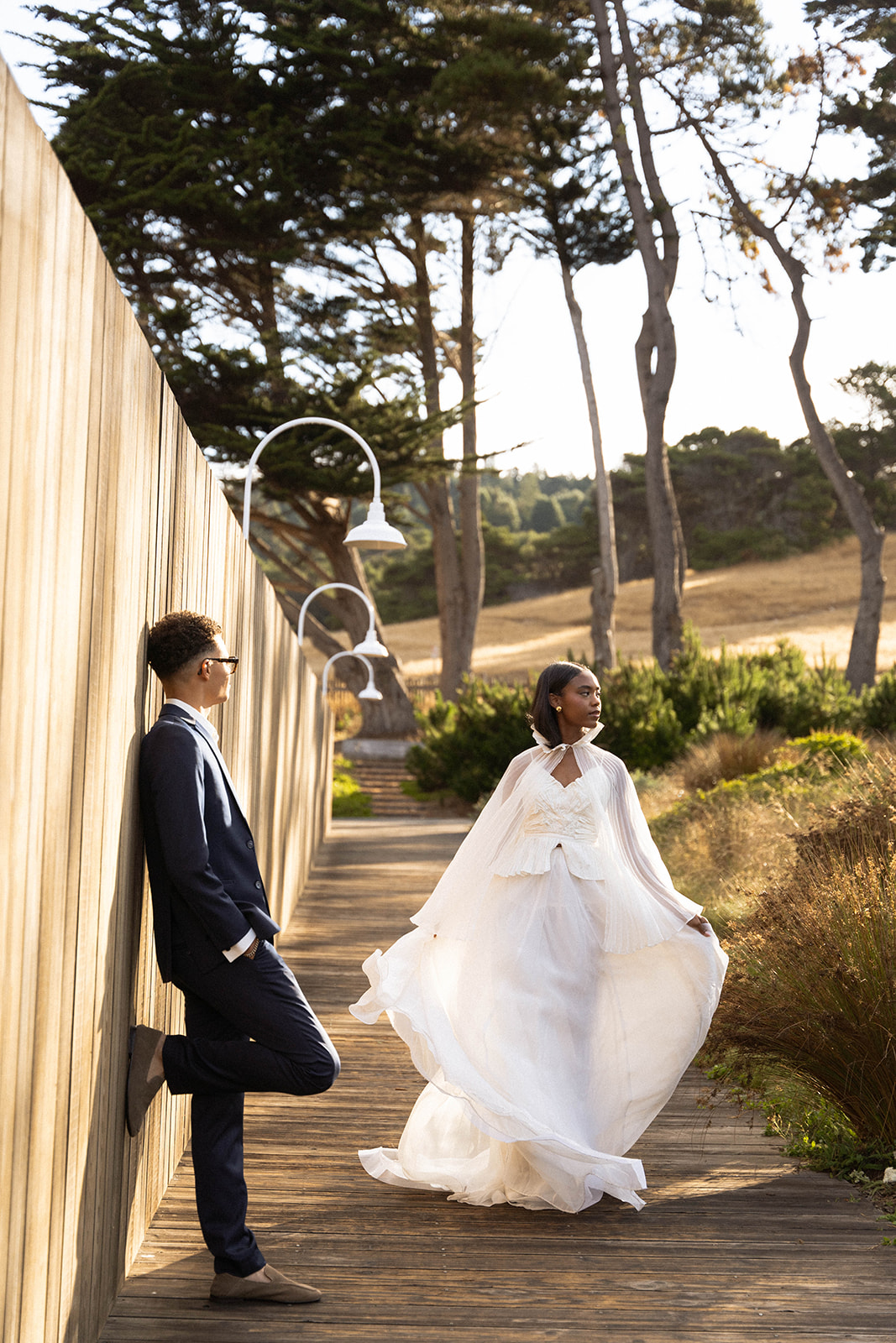 The bride and groom taking some editorial wedding portraits on a wooden path.