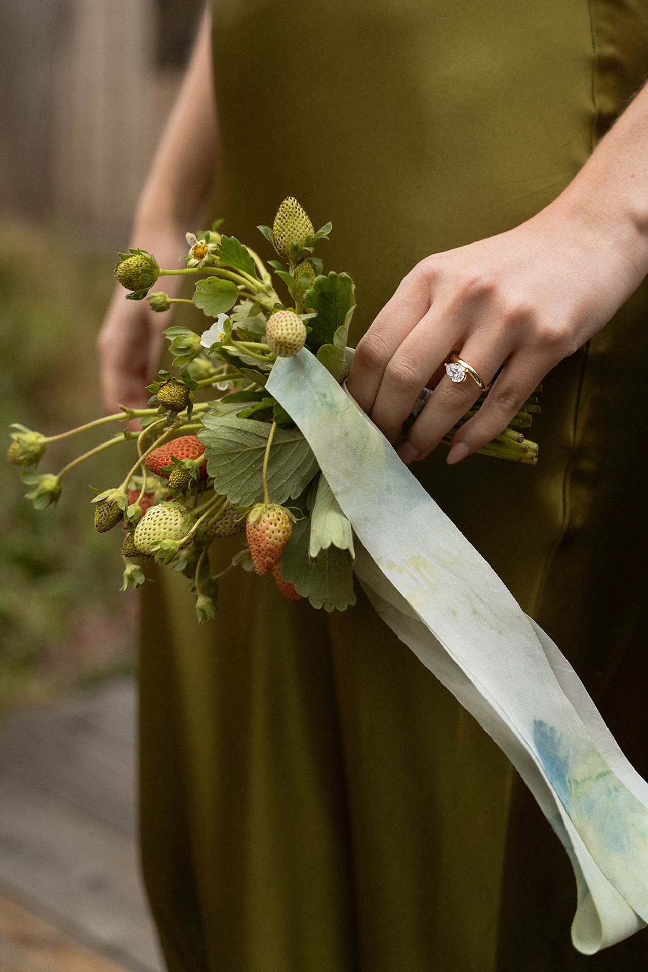 Bride holding a small bouquet of wild strawberries and greenery, highlighting thoughtful details that matter when planning a destination wedding.