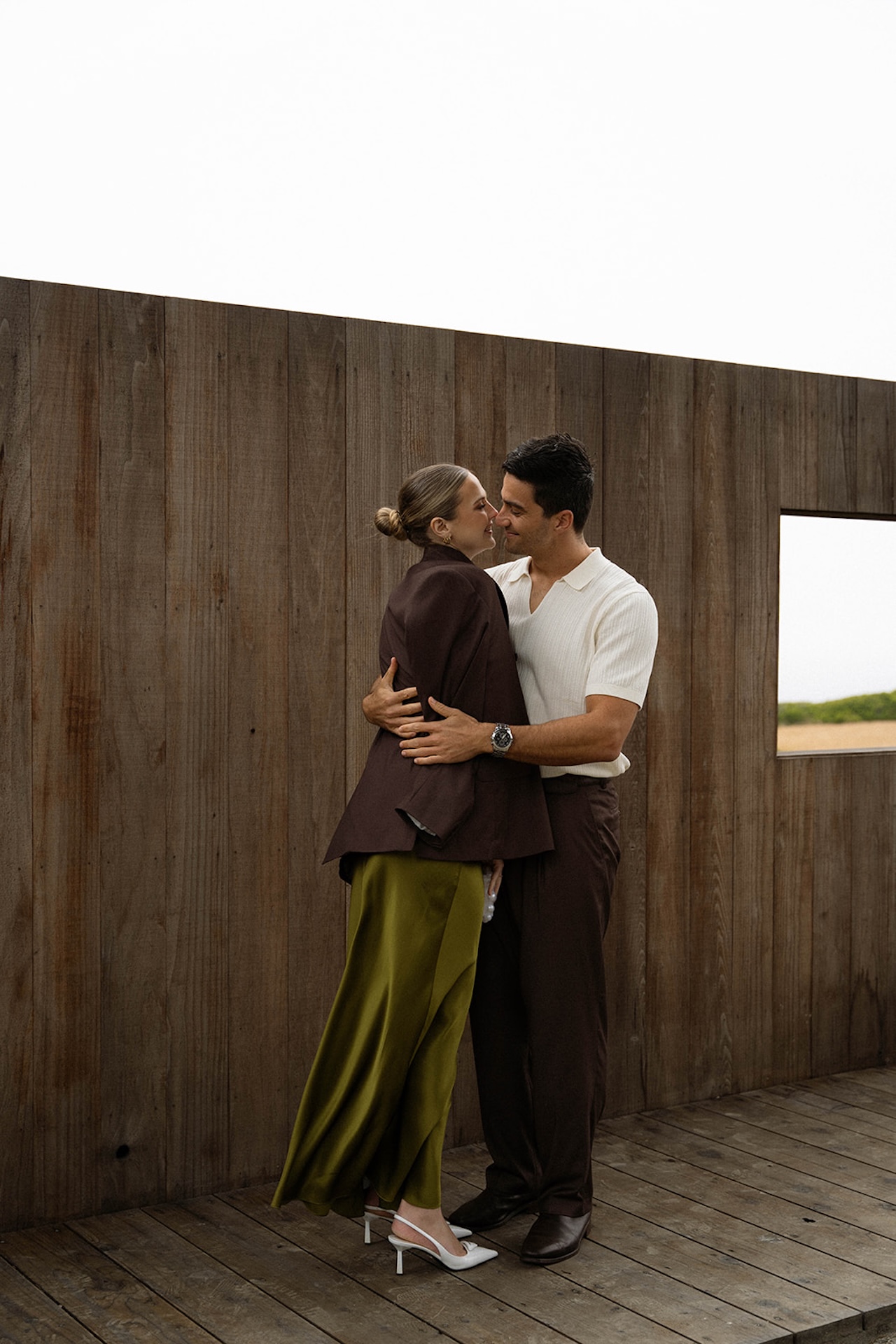 Bride and groom embracing on a wooden deck with ocean views beyond, capturing intimacy and connection while planning a destination wedding.