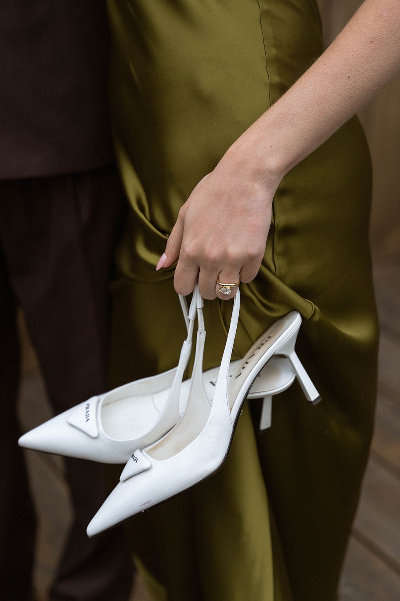 Close-up of the bride holding white heels and showing her engagement ring, a quiet moment that reflects the personal details couples consider when planning a destination wedding.