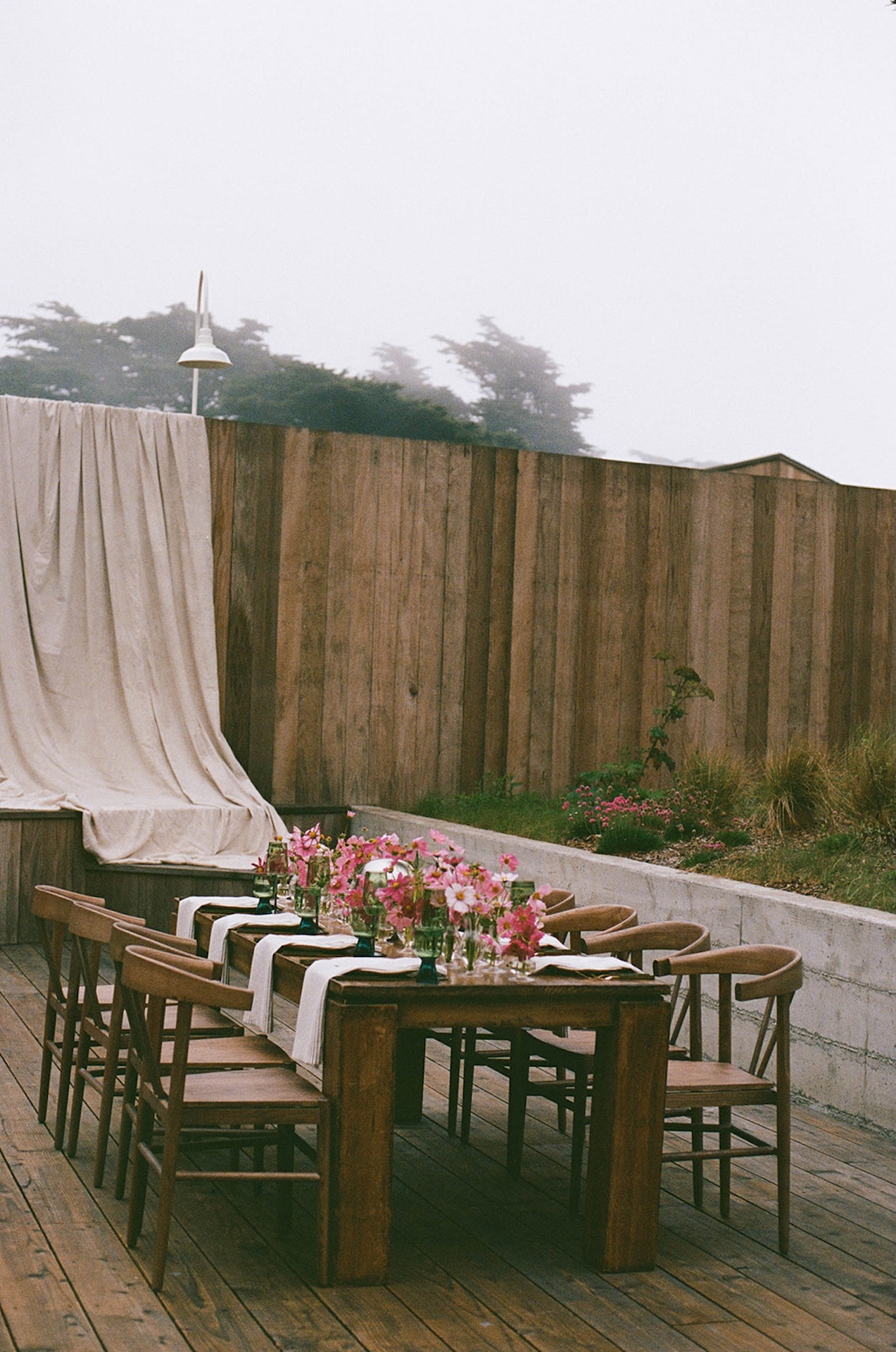 Close-up of a floral centerpiece with pink blooms and green glassware, highlighting refined table styling when planning a destination wedding.