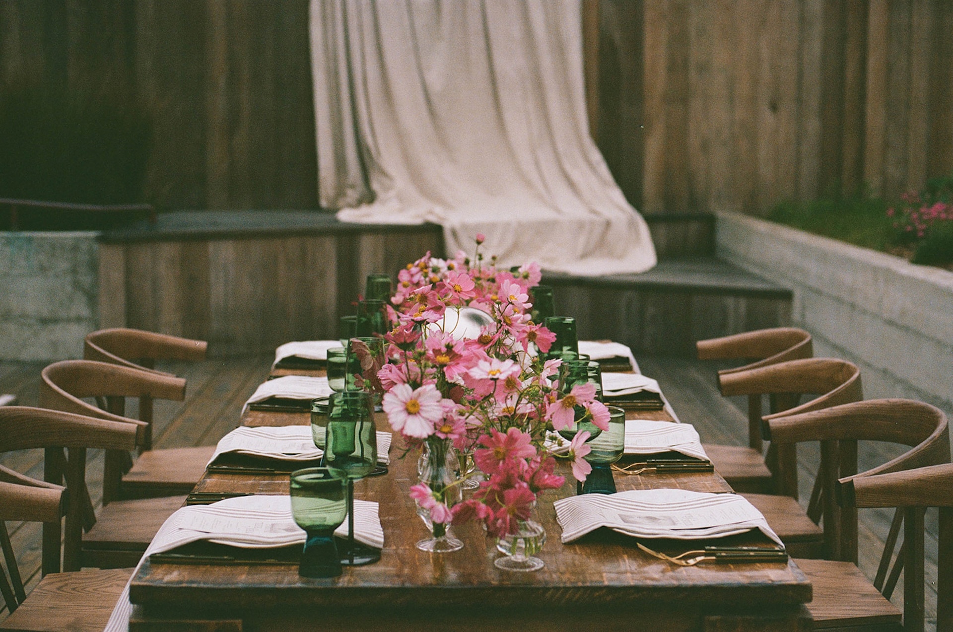 Close-up of a floral centerpiece with pink blooms and green glassware, highlighting refined table styling when planning a destination wedding.
