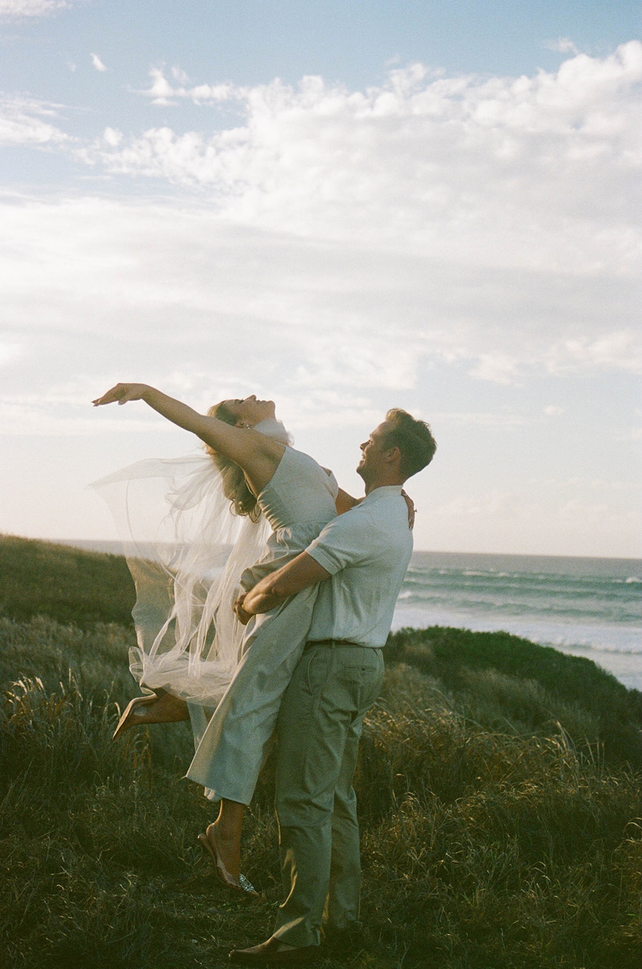 A playful lift near the coastline as one partner spins the other with arms outstretched, capturing joyful and movement-focused ideas for engagement photos on oahu.