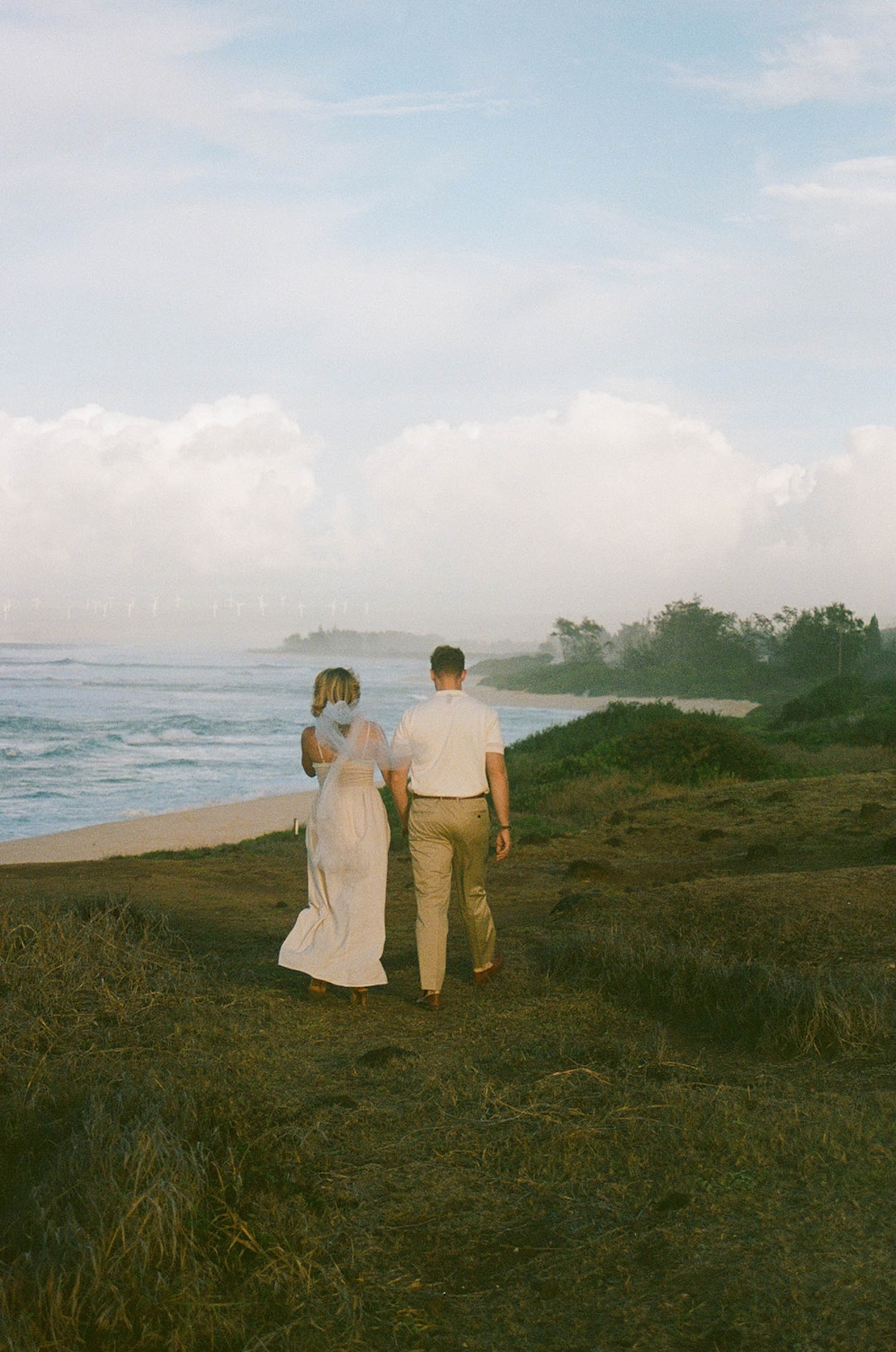The couple walking away hand in hand toward the coast, creating a relaxed and cinematic ending moment.