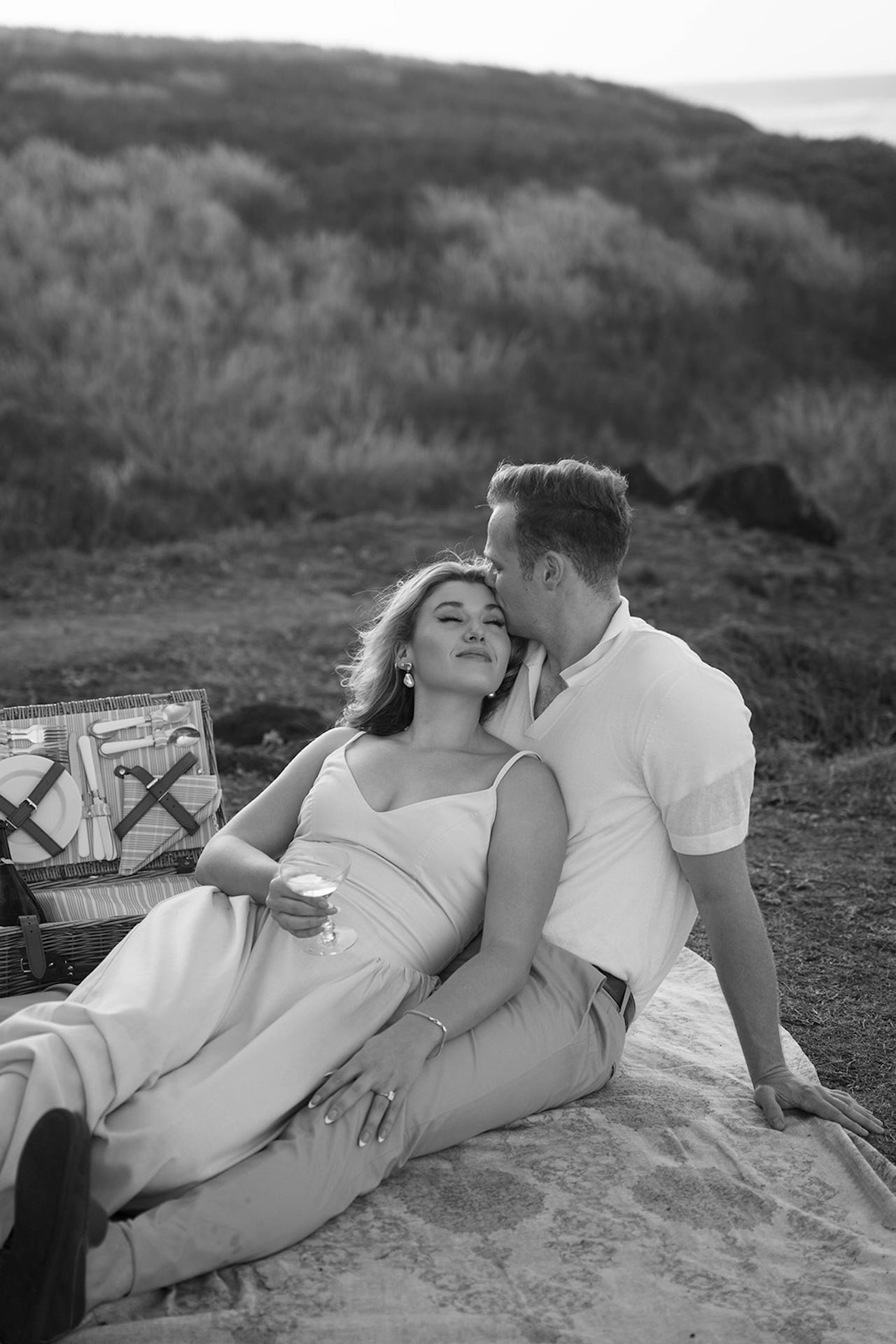 A black and white close-up of the couple leaning into each other on a picnic blanket, emphasizing quiet connection and timeless emotion.