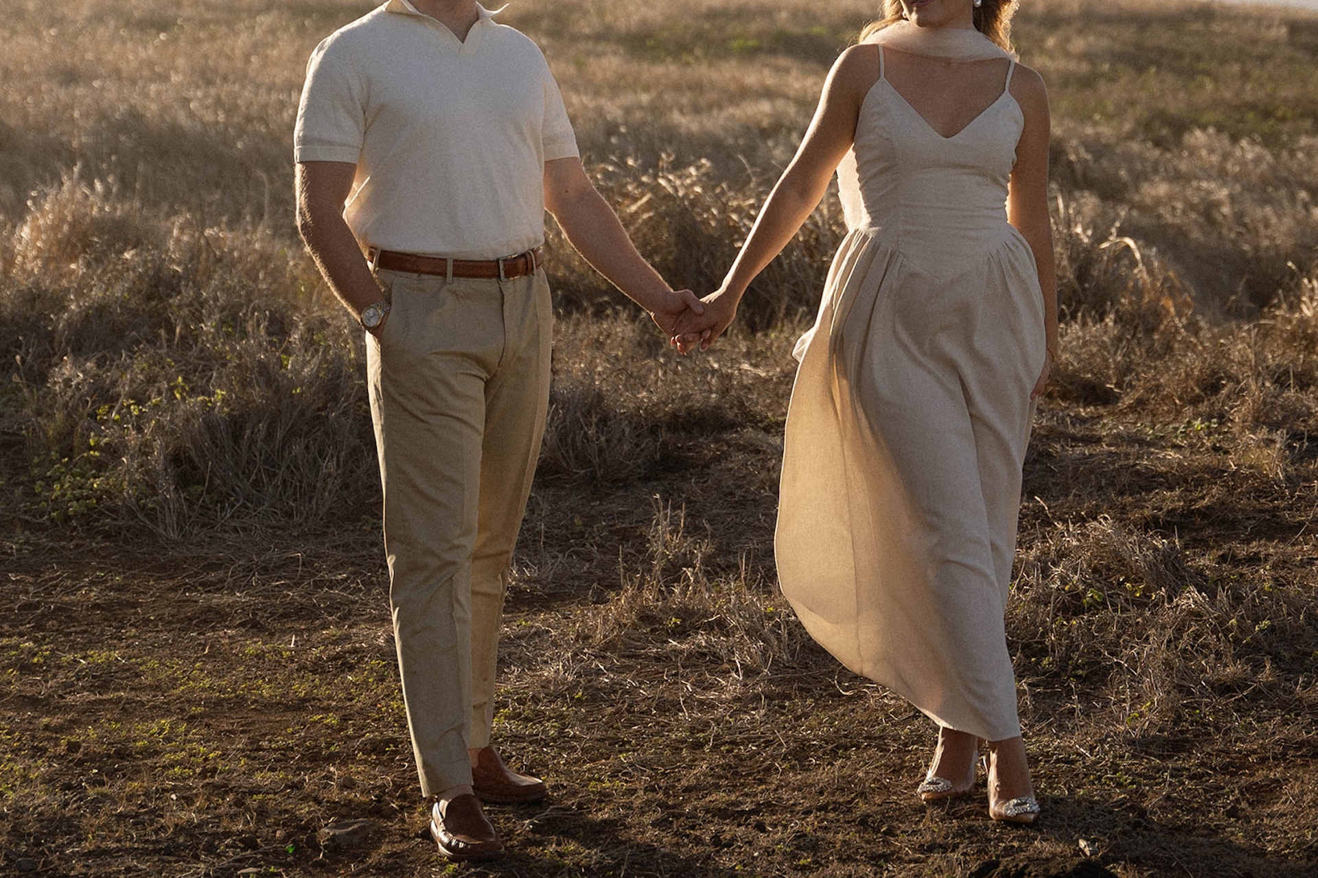 The couple holding hands mid-stride as fabric and hair catch the breeze, capturing effortless ideas for engagement photos on oahu.